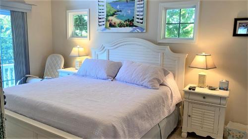 a bedroom with a white bed and two windows at Seamans Folly On Broad in Cape May