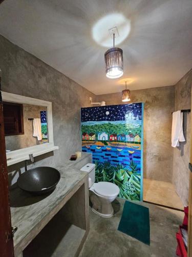 a bathroom with a sink and a toilet and a painting at Varanda do Mar Caraíva Oceanfront in Porto Seguro