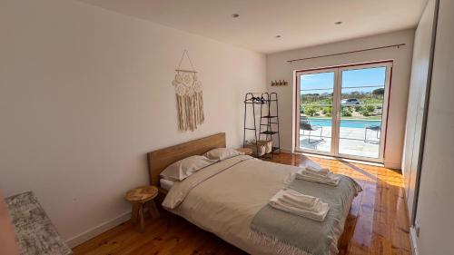 a bedroom with a bed and a view of a pool at Quinta Maria Cotovia in Porto Covo