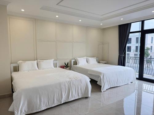 two beds in a white room with a window at Na homes coffee in Binh Hai