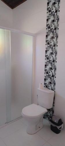 a bathroom with a toilet and a glass wall at Condominio Morada da Praia in Bertioga