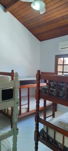 a room with two beds and a table and a ceiling at Condominio Morada da Praia in Bertioga
