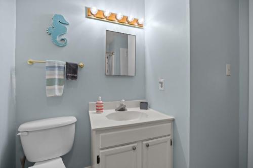 a bathroom with a white toilet and a sink at Tranquility By The Sea-Oceanside Condo in Salter Path