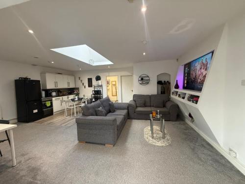 a living room with a couch and a kitchen at Private Apartment in Oldham