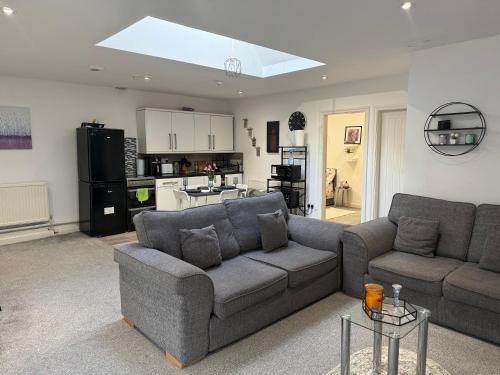 a living room with a couch and a kitchen at Private Apartment in Oldham