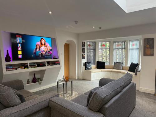 a living room with two couches and a flat screen tv at Private Apartment in Oldham