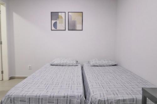 a bed in a white room with two pictures on the wall at Studio III - Centro Jundiaí - Ar Condicionado in Jundiaí