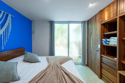 a bedroom with a bed with a blue wall at Private Jungle Villa with Full Kitchen & Pool Access in Tulum