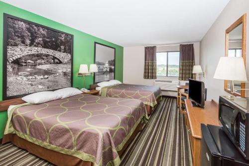 a hotel room with two beds and a flat screen tv at Super 8 by Wyndham Sioux City South in Sioux City