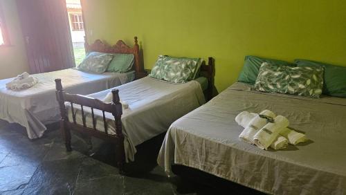 two beds in a room with green walls at Casa da Passagem in Cabo Frio