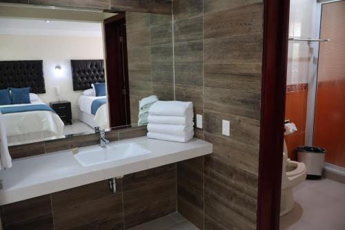 a bathroom with a sink and a mirror and a bed at Hotel Tierras Blancas in Valle de Bravo