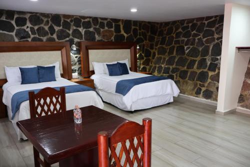 a hotel room with two beds and a table at Hotel Tierras Blancas in Valle de Bravo