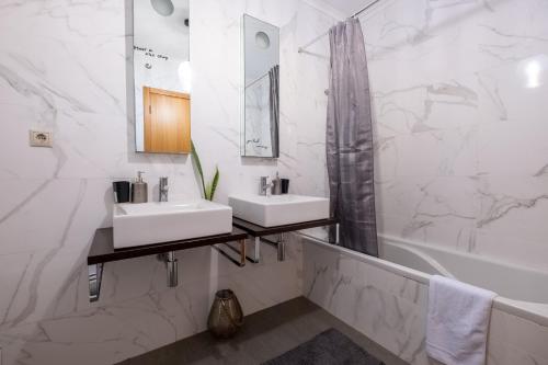 a bathroom with two sinks and a tub and a mirror at A casa da Girafa in Ponta Delgada