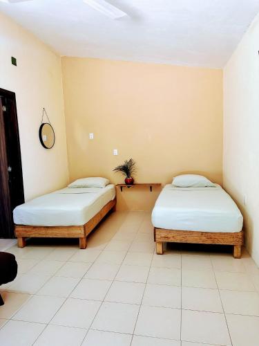 two beds sitting in a room with white tiles at Casa Brisas in Puerto Escondido