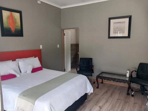 a bedroom with a large bed and two chairs at Donido's Place in Alberton