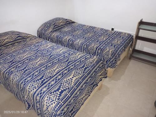 two beds sitting next to each other in a room at Comfortable, bright and compact in Tembladera