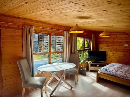 a room with a table and a bed and a television at Glebe Summer House in Osmington