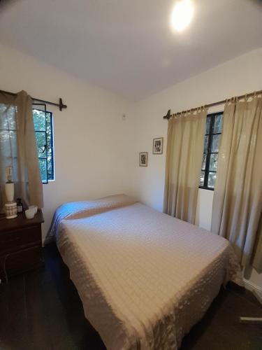 a bedroom with a bed and two windows at La Chaira in Santa Ana