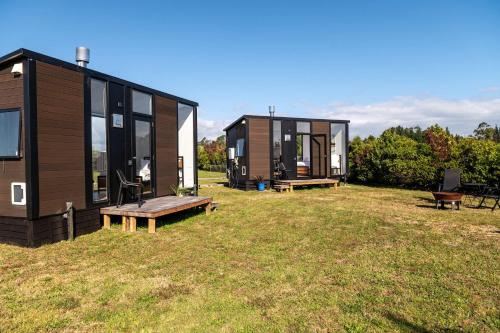 a couple of tiny houses sitting on top of a field at The Nest at Arahura Escape by Tiny Away in Kaihinu