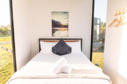a bedroom with a white bed with a window at The Nest at Arahura Escape by Tiny Away in Kaihinu