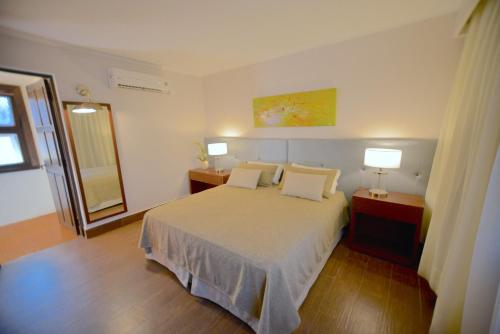 a bedroom with a bed with two lamps and a mirror at Hotel Guaminí Misión in Puerto Iguazú