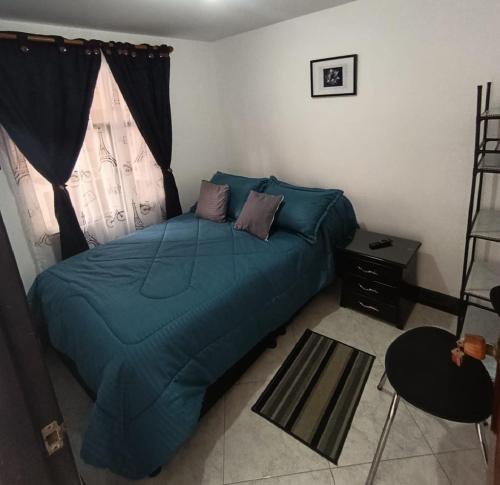 a bedroom with a bed with a blue comforter and a window at Hospedaje Donde Jaime-Choachí in Choachí