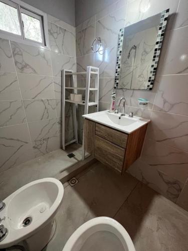 a bathroom with a sink and a toilet and a mirror at Cabaña Tres linas in Villa General Belgrano