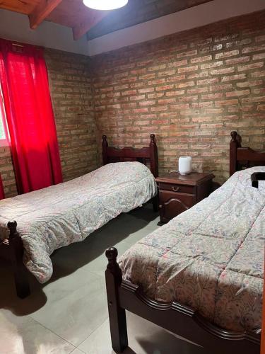 a bedroom with two beds and a brick wall at Cabaña Tres linas in Villa General Belgrano