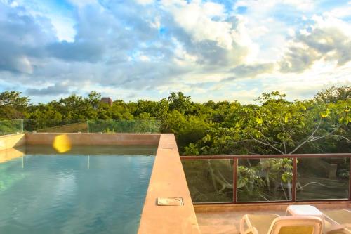 a swimming pool on a balcony with trees at Family Studio Suite with Kitchenette & Terrace - Santuario Hotel Boutique in Chemuyil