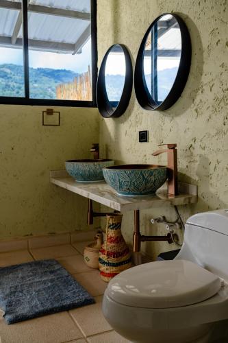 a bathroom with two sinks and a toilet with two mirrors at Villajesu Villeta in Villeta