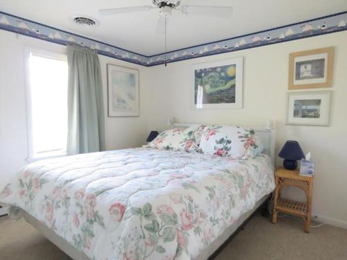 a bedroom with a bed with a floral comforter and a window at Parsons Folly Unit 3 in Cape May Point