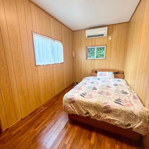 a bedroom with a bed in a room with wooden walls at ペンション波 in Ufugumui