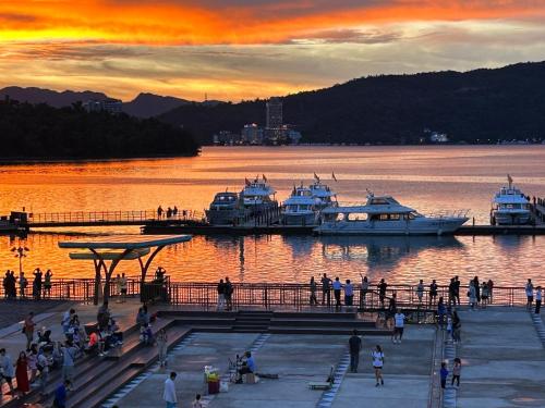 a group of people standing on a dock with boats in the water at Sun Moon Lake FRIDAY Inn Guest House in Yuchi