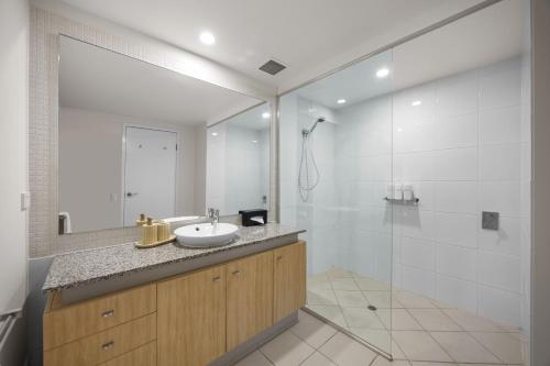 a bathroom with a sink and a shower with a mirror at Pelican Waters Golf Resort Sunshine Coast in Caloundra