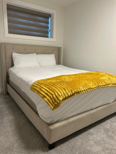 a bed with a yellow blanket on top of it at Lizzy cozy Basement suite in Airdrie