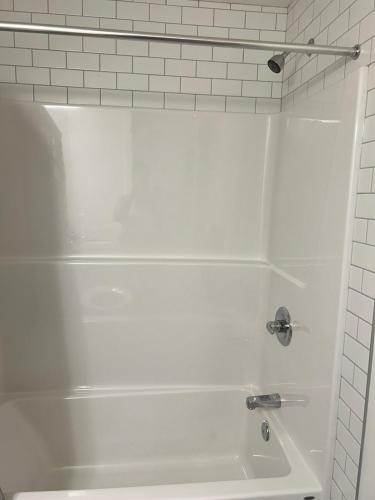 a white bath tub in a white tiled bathroom at Lizzy cozy Basement suite in Airdrie