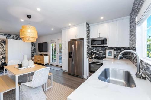 a kitchen with white cabinets and a stainless steel refrigerator at The Palomino - AMAZING Chic-Luxe, Private, Guest House - Pool, Sauna, Free Parking in Los Angeles