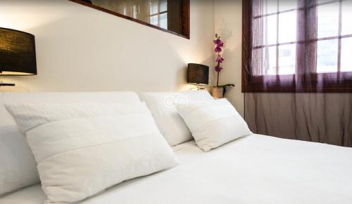 a white bed with white pillows and a window at Hotel Itxas Gain Getaria in Getaria