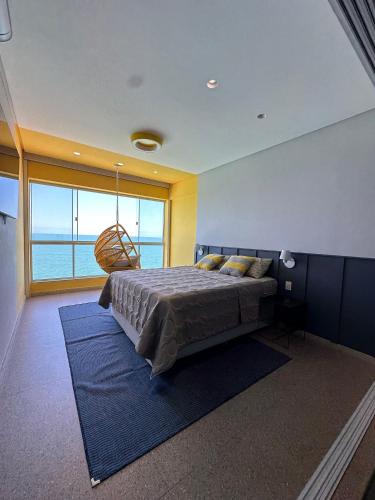 a bedroom with a large bed and a large window at Guarapari Center Aparts in Guarapari