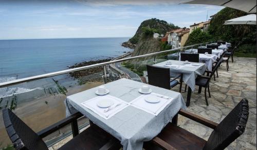 a row of tables on a balcony with the ocean at Hotel Itxas Gain Getaria in Getaria