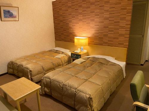 a hotel room with two beds and a table and a lamp at Kuji Grand Hotel in Kuji