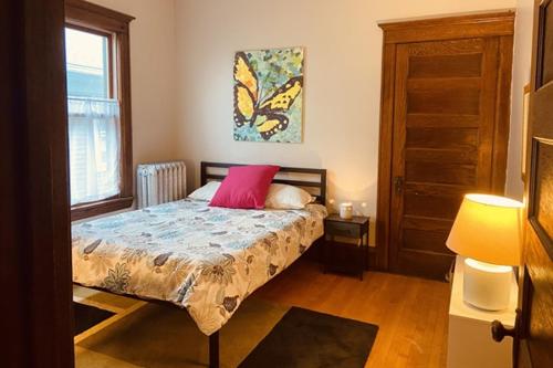 a bedroom with a bed with a pink pillow at Treetop Apartment in the Heart of MPLS in Minneapolis