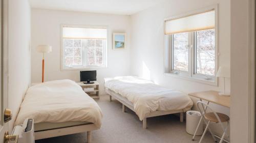 two beds in a room with two windows at Pension Himawari in Iizuna