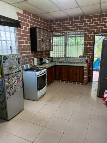 a kitchen with white appliances and a brick wall at La casa de ito la chorrera in La Chorrera