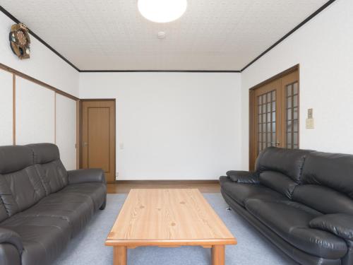 a living room with black leather couches and a wooden table at Slow Toya in Lake Toya