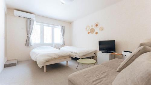 a living room with two beds and a couch at Pension Himawari in Iizuna