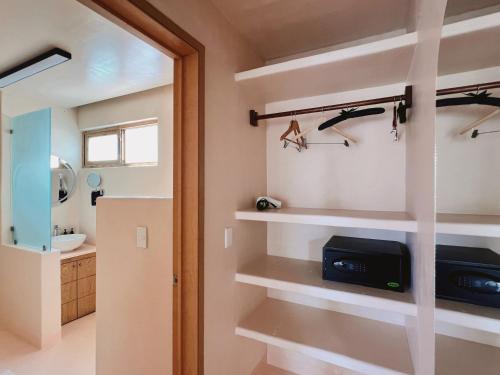 ein Badezimmer mit weißen Regalen und einem Fernseher in einem Zimmer in der Unterkunft Xeno Hotel Boutique in Playa Estacahuite