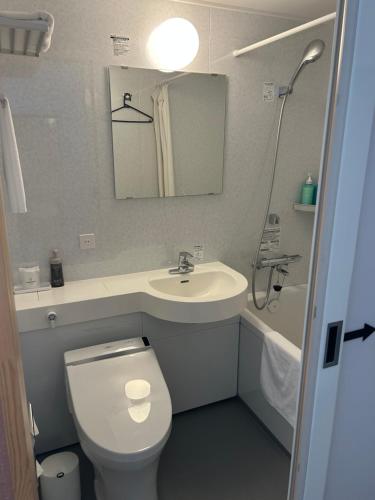 a small bathroom with a toilet and a sink at Kuji Grand Hotel in Kuji