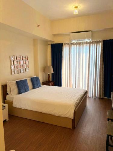 a bedroom with a large bed with blue pillows at Arlowes at 20f Grand Residences Cebu in Cebu City