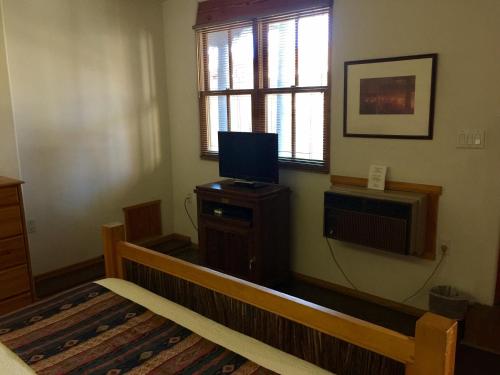 a living room with a tv and a wooden bench at Guadalupe Inn in Santa Fe